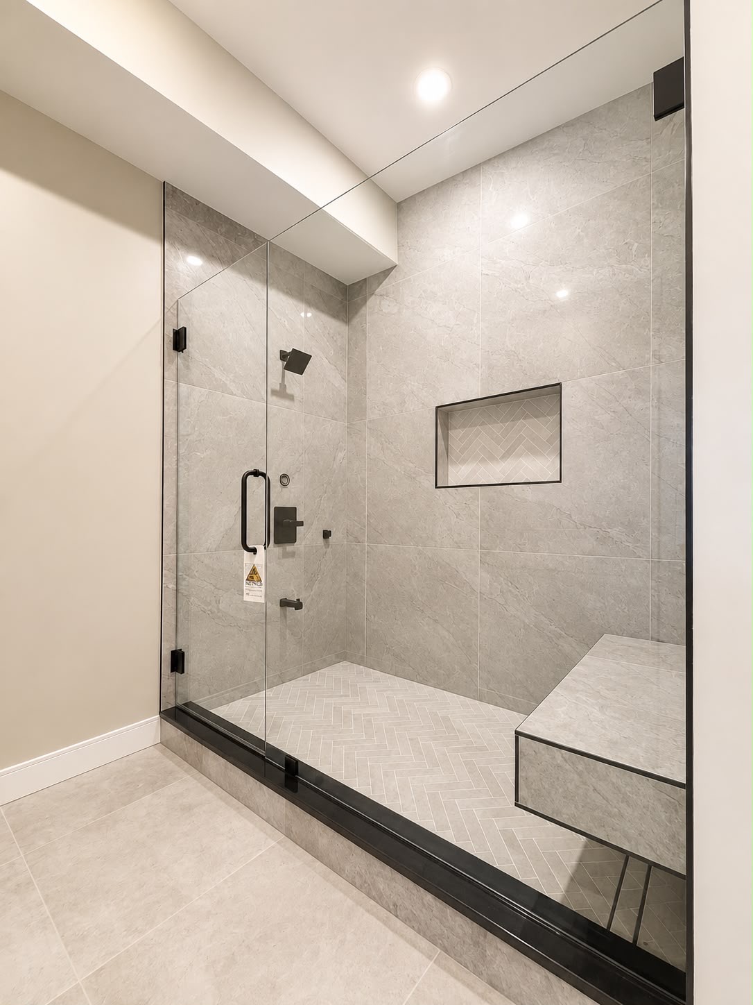 Stone shower with bench by Horus Glassworks — Black trim and hardware